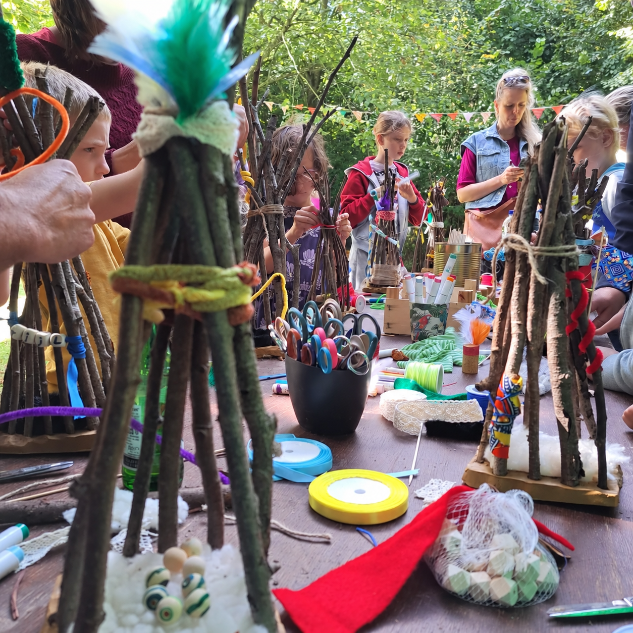 Kinderen maken tipi’s met takken en kleurrijke materialen tijdens Into the Wild